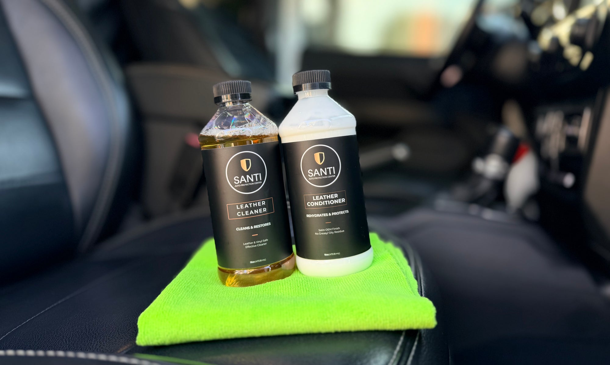 Two bottles of Santi leather care products on a green towel inside a car.