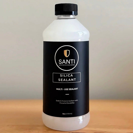 A bottle of Santi Silica Sealant Multi-Use Sealant, featuring a black label and black cap, placed on a wooden surface against a neutral gray background.