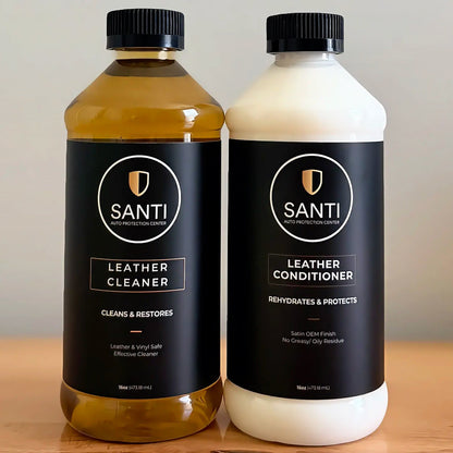 Two bottles of Santi Leather Care products on a wooden surface against a neutral beige background: a 500ml bottle of Leather Cleaner filled with amber liquid, and a 500ml bottle of Leather Conditioner with a white liquid.