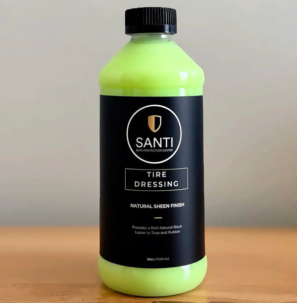 A bottle of Santi Tire Dressing in a bright neon yellow-green color with a black cap and a black label, sitting on a wooden surface against a neutral gray background.